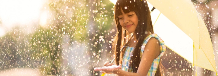 A young girl playing in the rain.