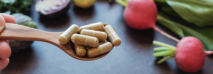 Chiropractic Cockeysville MD Supplements Supplement on a spoon with vegetables in the background.